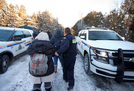 FILE PHOTO: A family from Yemen is taken into custody by Royal Canadian Mounted Police (RCMP) officers after walking across the U.S.-Canada border into Hemmingford, Quebec, Canada on February 14, 2017. REUTERS/Christinne Muschi/File Photo