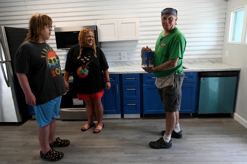Dustin Muir and his mother, Denise Jones, stand in the main room of their new tiny house build from shipping containers by Glen Gibellina. The cabinets and other details were painted a special blue in memory of Denise’s mother’s favorite “Blue suede” of Elvis fame.
