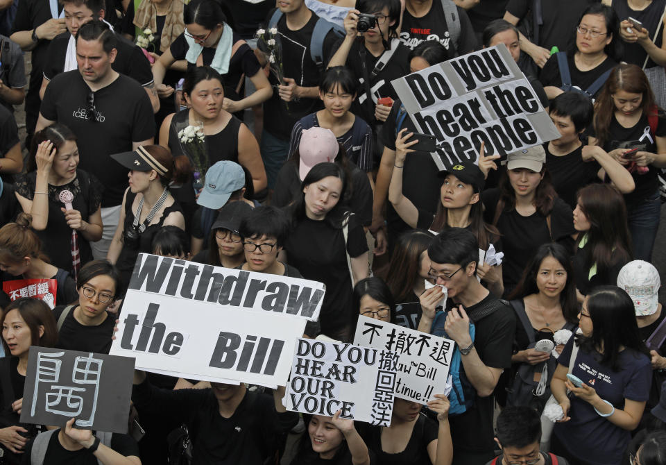FILE - In this Sunday, June 16, 2019, file photo, protesters holding posters and flowers march on the streets to protest against the unpopular extradition bill in Hong Kong. (AP Photo/Vincent Yu, File)
