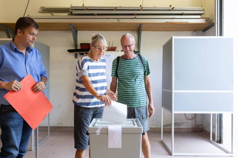 Barbara and Norbert Stein throw their ballots into the ballot box at the polling station in Fire Station 3 Ilmenau-Roda, together with polling station manager Stefan Sandmann. The state elections in Thuringia will take place on Sunday. Michael Reichel/dpa