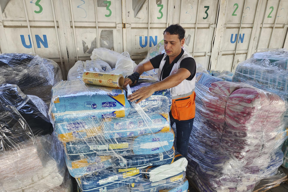 FILE - United Nations and Red Crescent workers prepare the aid for distribution to Palestinians at UNRWA warehouse in Deir Al-Balah, Gaza Strip, on Monday, Oct. 23, 2023. With the Israel-Hamas war in its second month and more than 10,000 people killed in Gaza, trapped civilians are struggling to survive without electricity or running water. Each day has become a mind-numbing cycle of searching for bread and water and waiting in lines. A sense of desperation has strained Gaza's close-knit society. (AP Photo/Hassan Eslaiah, File)