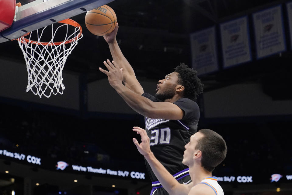 Sacramento Kings center Damian Jones (30) shoots in front of Oklahoma City Thunder center Aleksej Pokusevski, right, in the first half of an NBA basketball game Monday, Feb. 28, 2022, in Oklahoma City. (AP Photo/Sue Ogrocki)