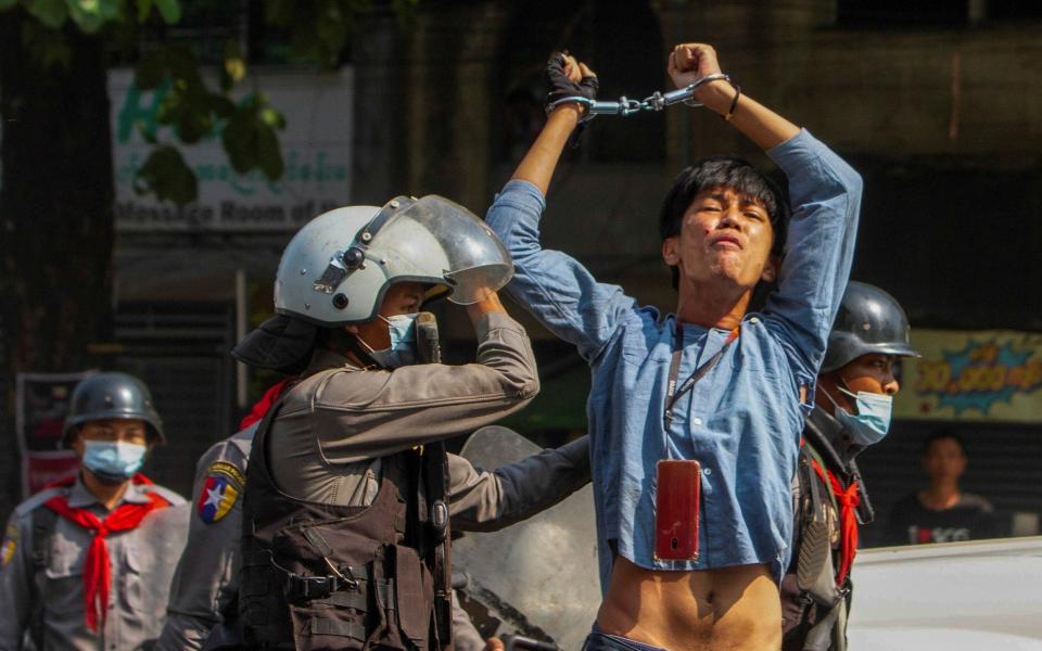 A pro-democracy protester is detained by riot police officers during a rally against the military coup in Yangon - REUTERS