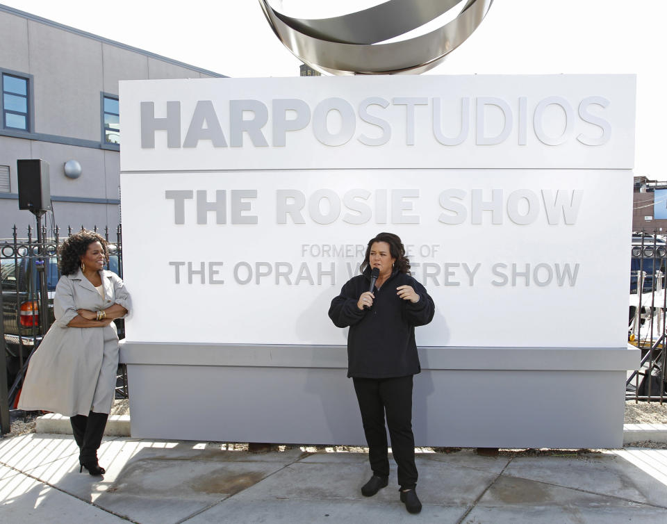 FILE-This Sept. 15, 2011, file photo shows Rosie O'Donnell, right, with Oprah Winfrey looking on, speaking to the media after the unveiling of a new sign outside Harpo Studios welcoming "The Rosie Show," to the studio in Chicago. Winfrey is selling Harpo Studios in Chicago to a developer, but the studio will remain on the property for another two years. Harpo Inc. said in a statement that it has entered into a purchasing agreement with Sterling Bay Cos. for the four-building campus on Chicago's West Side. (AP Photo/M. Spencer Green, File)