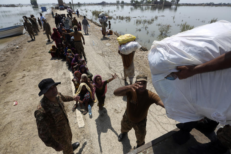 Aid is distributed to victims of heavy flooding from monsoon rains in the Qambar Shahdadkot district of Sindh Province, Pakistan, Friday, Sept. 9, 2022. U.N. Secretary-General Antonio Guterres appealed to the world for help for cash-strapped Pakistan after arriving in the country Friday to see the climate-induced devastation from months of deadly record floods. (AP Photo/Fareed Khan)