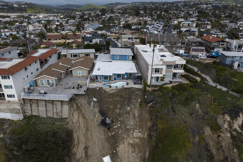 In this image taken with a drone, a residential swimming pool hangs on a cliffside after a landslide occurred in San Clemente, Calif., Thursday, March 16, 2023. (AP Photo/Jae C. Hong)