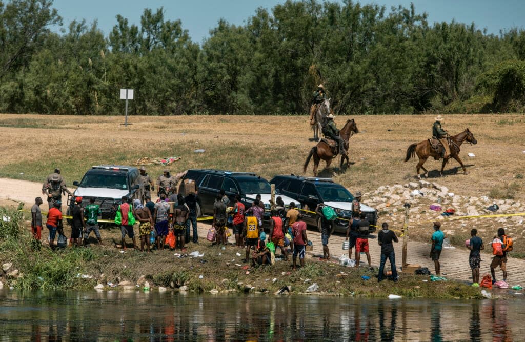 U.S. Border Patrol officers contain a group of migrants on the shore of the Rio Grande after they crossed from Ciudad Acuña, Mexico, into Del Rio, Texas, Sept. 19, 2021. Border Patrol agents on horseback engaged in “unnecessary use of force” against non-threatening Haitian migrants but didn’t whip any with their reins, according to a federal investigation of chaotic scenes there last fall. (AP Photo/Felix Marquez, File)