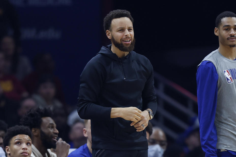 Golden State Warriors guard Stephen Curry, center, watches from the bench during the first half of an NBA basketball game against the Cleveland Cavaliers, Friday, Jan. 20, 2023, in Cleveland. (AP Photo/Ron Schwane)