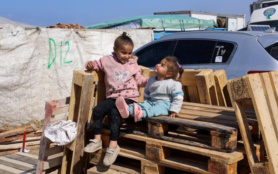 Displaced children sit on wooden pallets, as displaced Palestinians, who fled their houses due to Israeli strikes, take shelter in a tent camp amid the ongoing conflict between Israel and Hamas, near the border with Egypt in Rafah in the southern Gaza Strip