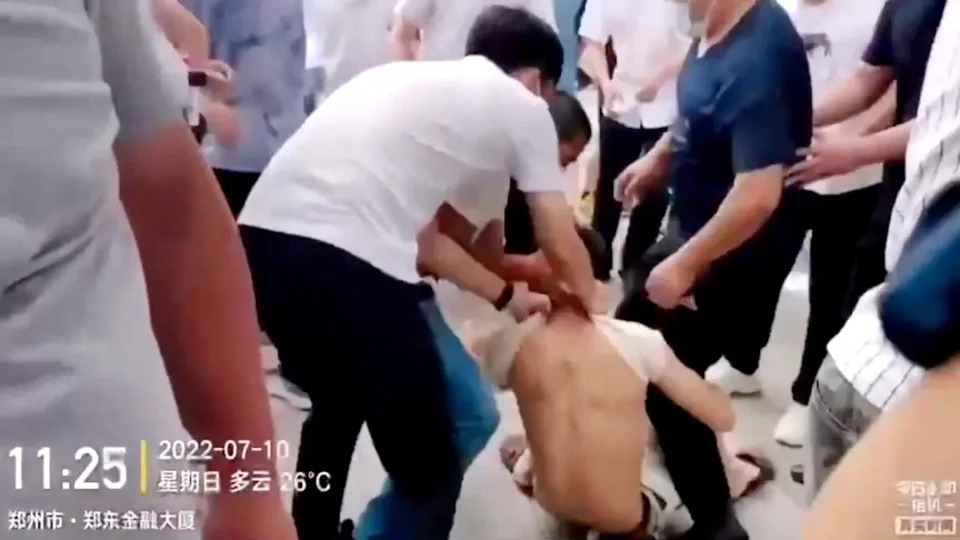 Plain-clothed security personnel pull on a demonstrator's shirt while dragging him away during a protest over the freezing of deposits by some rural-based banks, outside a People's Bank of China building in Zhengzhou, Henan province, China July 10, 2022, in this screengrab from video obtained by REUTERS ATTENTION EDITORS - THIS IMAGE HAS BEEN SUPPLIED BY A THIRD PARTY.