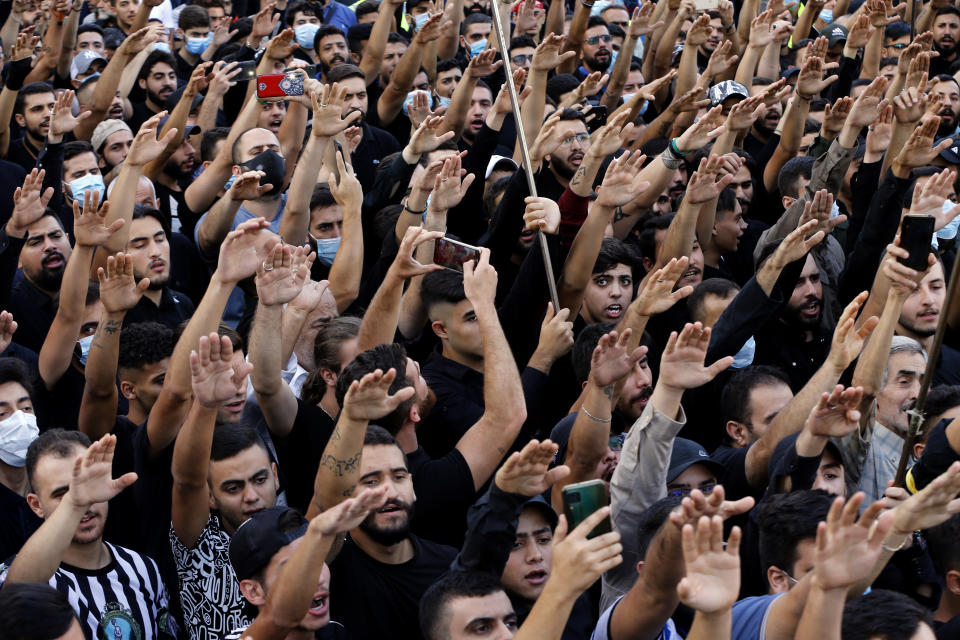 Mourners chant slogans as they rise their hands during the funeral of three Hezbollah supporters who were killed during Thursday clashes, in the southern Beirut suburb of Dahiyeh, Lebanon, Friday, Oct. 15, 2021. The government called for a day of mourning following the armed clashes, in which gunmen used automatic weapons and rocket-propelled grenades on the streets of the capital, echoing the nation's darkest era of the 1975-90 civil war. (AP Photo/Bilal Hussein)