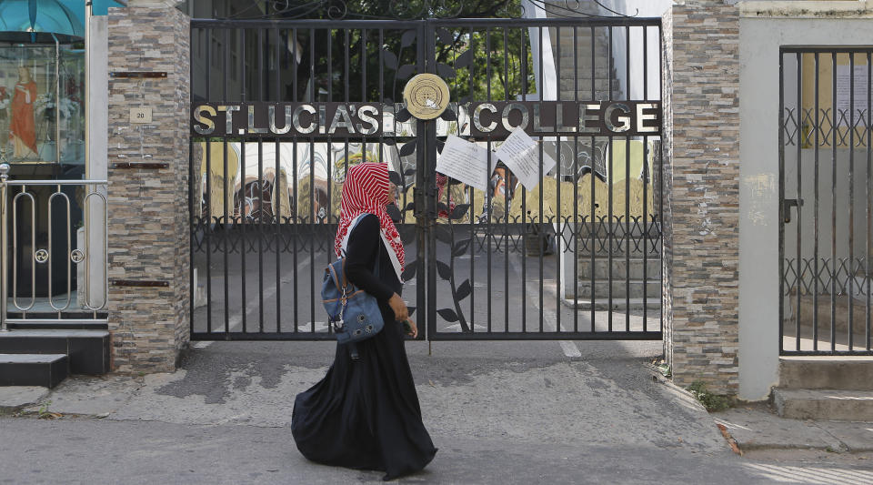 In this Sunday, May 12, 2019, photo, a Sri Lankan Muslim woman walks past St. Lucia's College in Colombo, Sri Lanka. Catholic officials and parents in Sri Lanka are hopeful that church-run schools will begin to reopen soon for the first time since April’s devastating Easter Sunday attacks on churches and hotels. (AP Photo/Eranga Jayawardena)