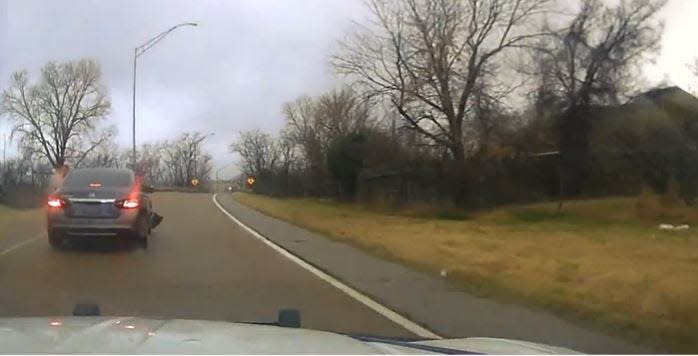 This screen shot from a dashcam video related to the fatal shootings of Terrance Dogan and John Henry Taylor appears to show someone leaning out of a car and firing shots at a police vehicle.