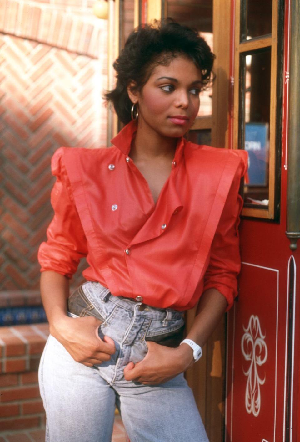 <p>Janet Jackson embraces power shoulders in a red top tucked into high-waisted denim. </p>