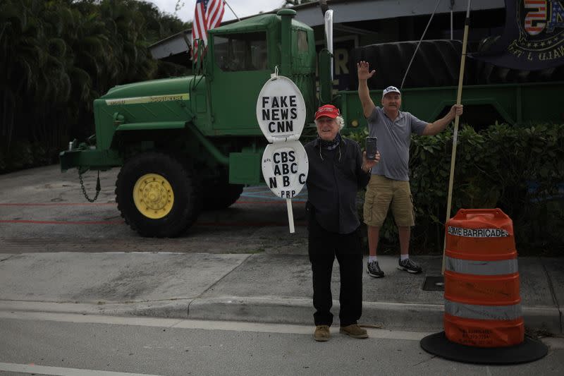 Supporters of President Trump display signs as the presidential motorcade passes through West Palm Beach