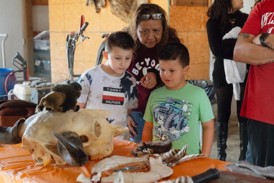 Andrea Poncho, affiliated with the Alabama–Coushatta Tribe of Texas, shows her sons Waylon and Gunnar a table displaying the various ways bison can be utilized.