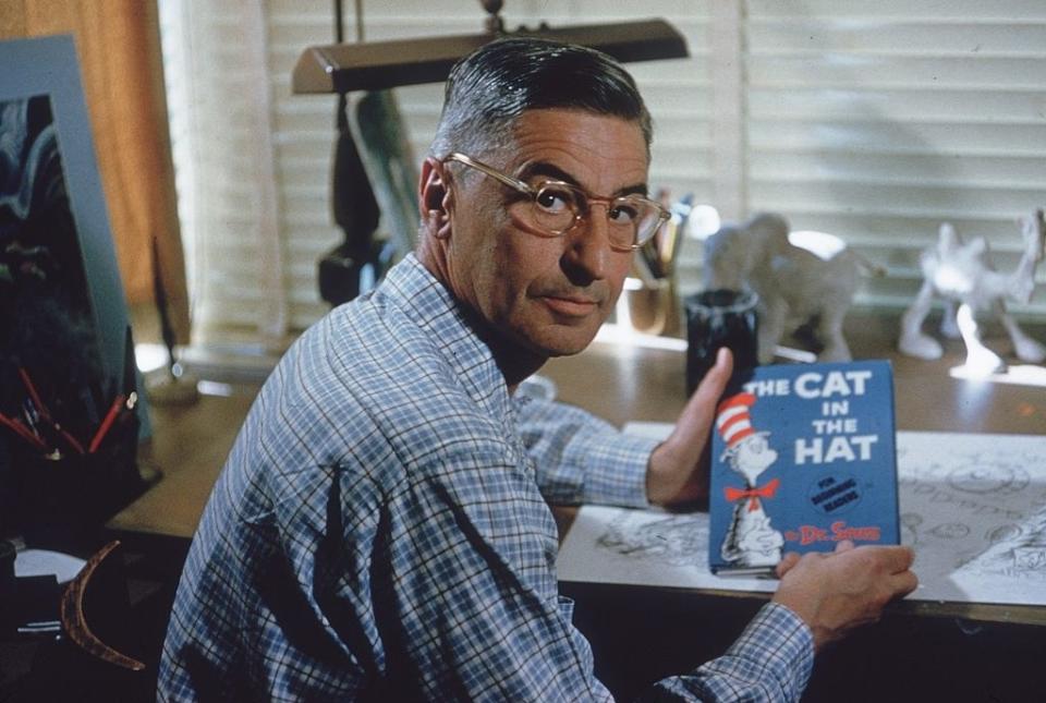 Dr. Seuss holding a copy of "The Cat in the Hat."