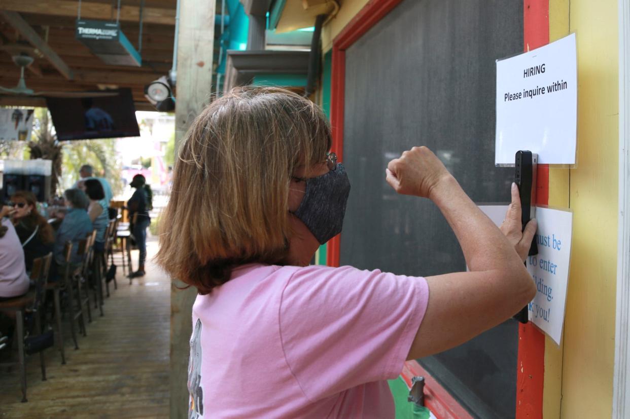 Debbie Dyess staples up a Help Wanted sign at the North Beach Bar and Grill on Tybee.