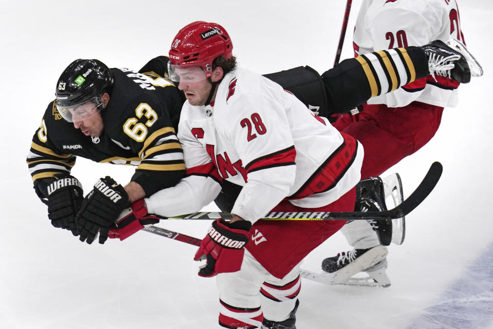 Boston Bruins left wing Brad Marchand (63) flies through the air after being tripped by Carolina Hurricanes left wing Brendan Lemieux (28) during the second period of an NHL hockey game, Wednesday, Jan. 24, 2024, in Boston. (AP Photo/Charles Krupa)