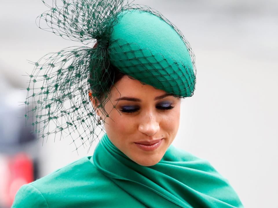 Meghan Markle wearing a green dress and hat looking down