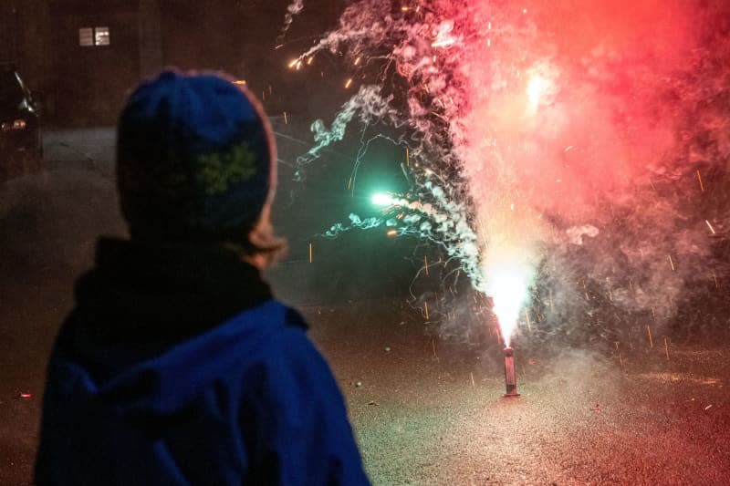 A boy watches colourful fireworks on a street in Memmelsdorf as people celebrate the New Year. Pia Bayer/dpa