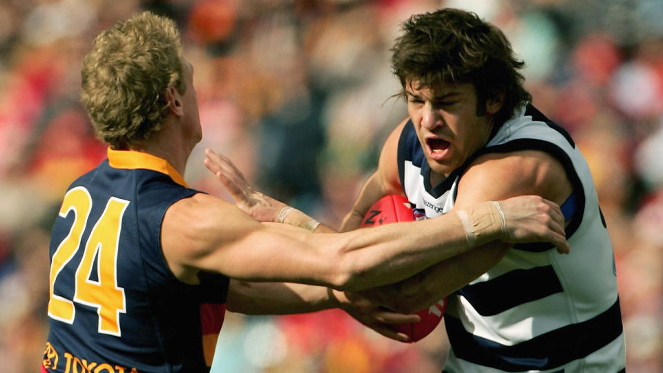 Max Rooke fends off an opponent during a 2006 AFL match for Geelong.