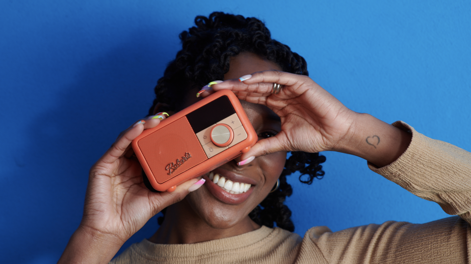 Roberts Revival Petite 2 in orange, held by a woman in a blue room