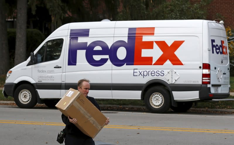 A FedEx delivery worker carries a package for a delivery in Wilmette