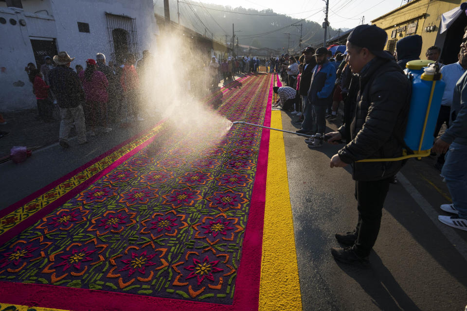 Miembros de la familia Álvarez ultiman los detalles de su alfombra de aserrín en preparación para la procesión de Semana Santa en Antigua, Guatemala, el Viernes Santo, 29 de marzo de 2024. (AP Foto/Moisés Castillo)