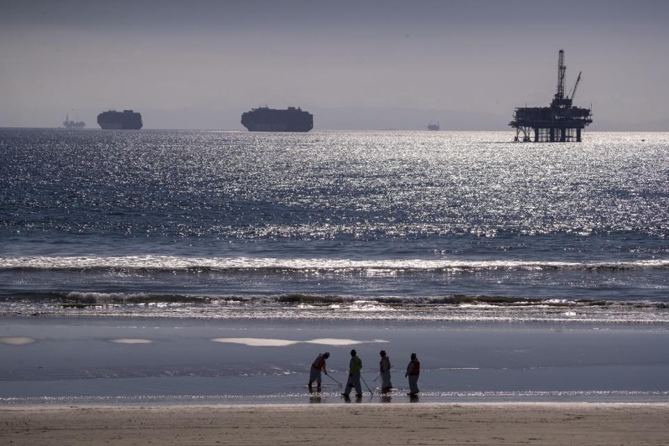 Container ships and an oil derrick line the horizon.