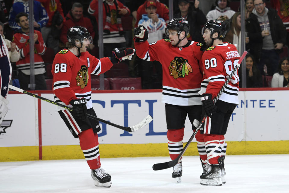 Chicago Blackhawks' Max Domi (13) celebrates with Patrick Kane (88) and Tyler Johnson (90) after scoring against the Columbus Blue Jackets during the first period of an NHL hockey game Friday, Dec. 23, 2022, in Chicago. (AP Photo/Paul Beaty)