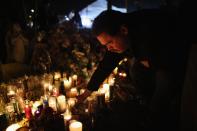 NEWTOWN, CT - DECEMBER 18: A mourner places a candle while visiting a makeshift memorial for shooting victims on December 18, 2012 in Newtown, Connecticut. Funeral services were held in Newtown Tuesday for Jessica Rekos and James Mattioli, both age six, four days after 20 children and six adults were killed at Sandy Hook Elementary School. (Photo by John Moore/Getty Images)