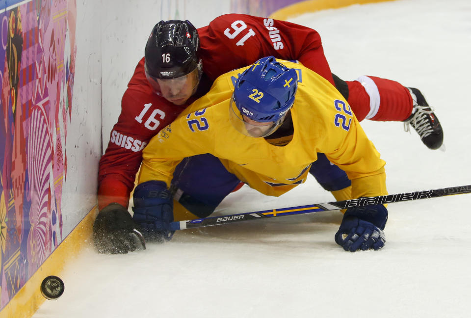 Switzerland defenseman Raphael Diaz and Sweden forward Daniel Sedin fall to the ice as they fight for the puck in the first period of a men's ice hockey game at the 2014 Winter Olympics, Friday, Feb. 14, 2014, in Sochi, Russia. (AP Photo/Mark Humphrey)
