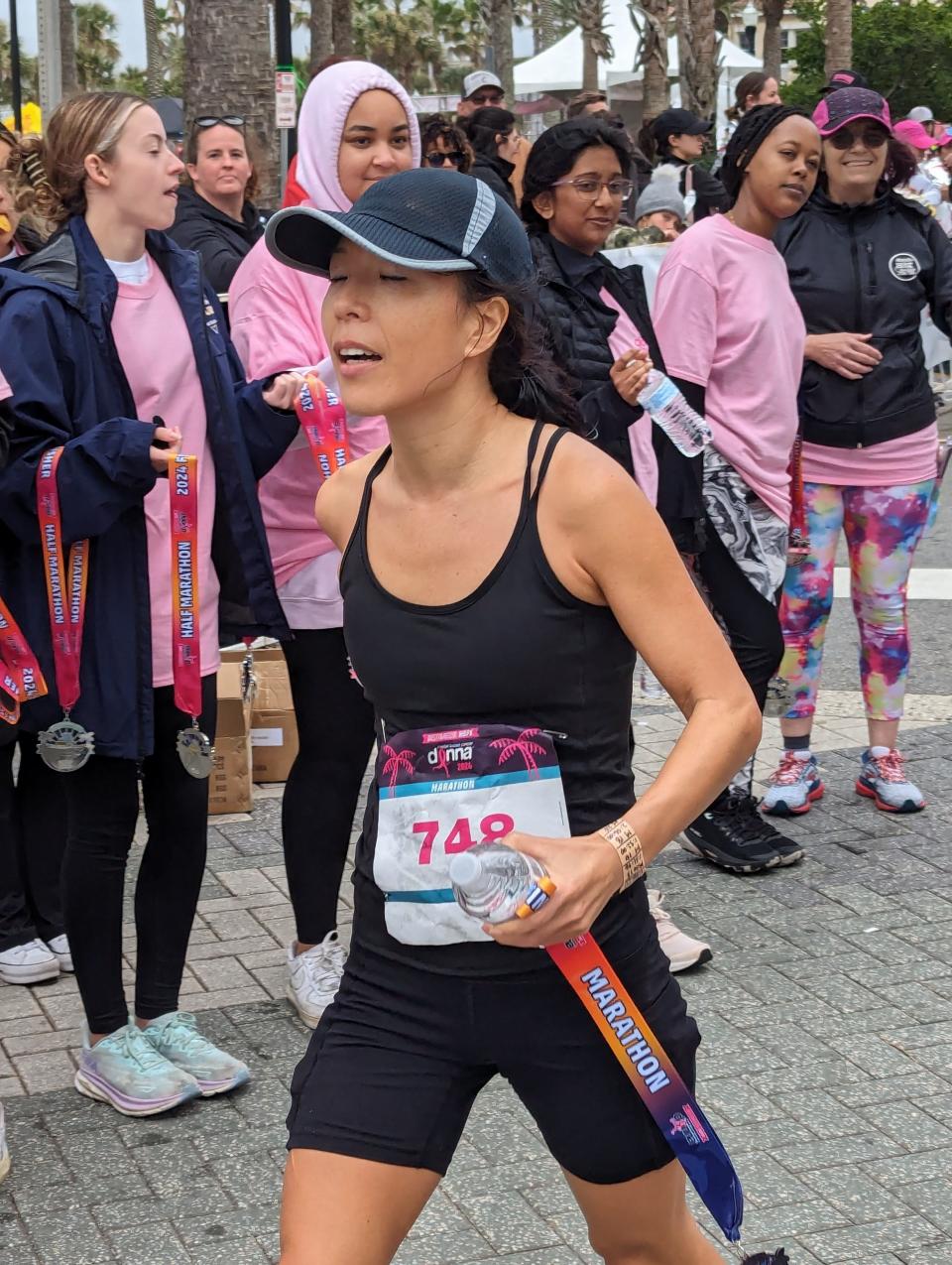 Kaori Alexander grabs a water bottle after crossing the line to win the women's race at the Donna Marathon in Jacksonville Beach.