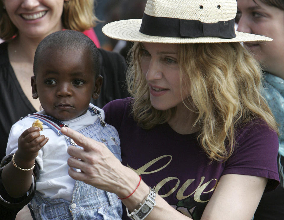 En esta foto del 19 de abril del 2007, Madonna carga a su hijo adoptivo David Banda en Masekese, Malawi. La Reina del Pop es también una mamá amante del fútbol que planea abrir una academia en el país africano. La iniciativa fue inspirada por Banda, quien tiene ambiciones de llegar a ser un futbolista profesional y está en la academia juvenil del club portugués Benfica. (AP Foto/Karel Prinsloo, Archivo)