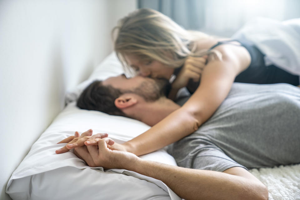 A man and woman in bed and kissing