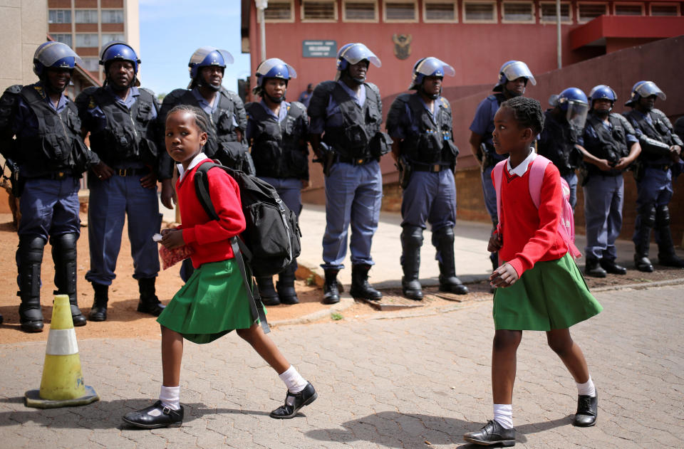 School girls walk past riot police standing guard outside Hillbrow magistrate court during an appearance of students who were arrested during a protest demanding free education at the Johannesburg's University of the Witwatersrand, South Africa, October 12, 2016.&nbsp;