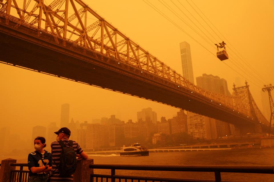 People wear protective masks as the Roosevelt Island Tram crosses the East River while haze and smoke from the Canadian wildfires shroud the Manhattan skyline (REUTERS)