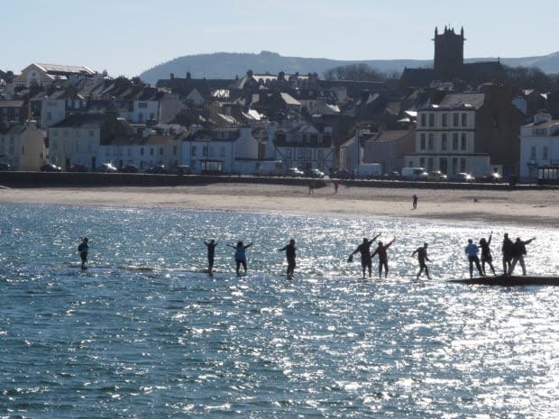 Beachgoers walk along a tidal causeway in the town of Peel on the Isle of Man on Monday, March 26, 2012. (Raphael Satter/Associated Press - image credit)