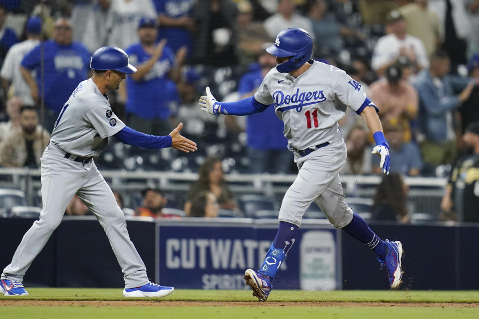 Los Angeles Dodgers' AJ Pollock, right, reacts with third base coach Dino Ebel after hitting a two-run home run during the sixteenth inning of a baseball game against the San Diego Padres, Thursday, Aug. 26, 2021, in San Diego. (AP Photo/Gregory Bull)