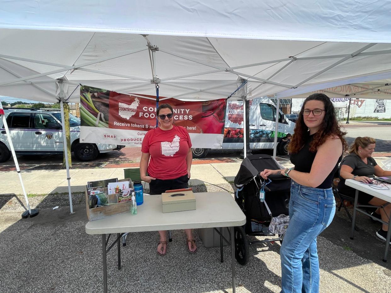 Barberton resident Ivori Spartan, right, visits the Countryside Food Access tent at the Barberton Farmers Market. Jenna Eastman. director of local food programs for the organization, looks on.