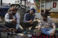 Gurpreet Singh, 27, a Biotechnology student from a farming family, center, makes flat bread for breakfast as they block a major highway protesting against new farming laws, at the Delhi-Haryana state border, India, Tuesday, Dec. 1, 2020. "India is in a recession. There are hardly any jobs and our country's secular fabric is in tatters," said Singh. "At a time when India needs a healing touch, Modi is coming up with divisive, controversial laws. This is unacceptable and defies our constitutional values." (AP Photo/Altaf Qadri)