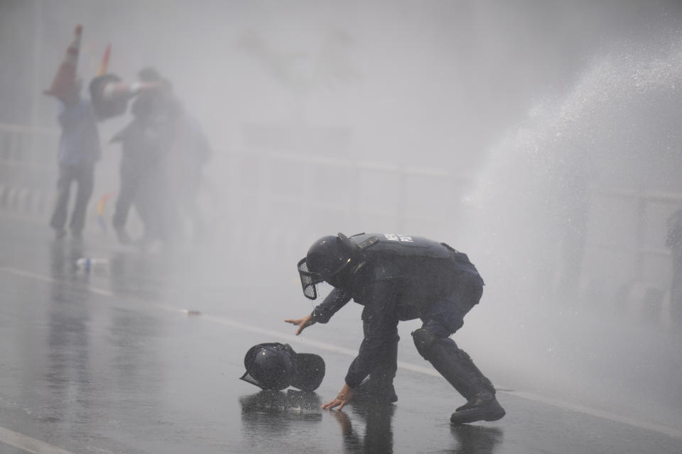 A policeman tries to grab his friend's helmet during a protest demanding a restoration of Nepal's monarchy in Kathmandu, Nepal, Tuesday, April 9, 2024. Riot police used batons and tear gas to halt thousands of supporters of Nepal's former king demanding the restoration of the monarchy and the nation's former status as a Hindu state. Weeks of street protests in 2006 forced then King Gyanendra to abandon his authoritarian rule and introduce democracy. (AP Photo/Niranjan Shrestha)