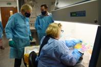 Britain's Prime Minister Boris Johnson (L) wears PPE (Personal Protective Equipment) as he visits the Lighthouse Laboratory used for processing PCR samples at the Queen Elizabeth University Hospital campus in Glasgow, Scotland on January 28, 2021, during a COVID-19 related visit to the country. - Prime Minister Boris Johnson headed to Scotland on Thursday to praise the United Kingdom's collective response to coronavirus, in a bid to counter record support for independence. (Photo by Jeff J Mitchell / POOL / AFP) (Photo by JEFF J MITCHELL/POOL/AFP via Getty Images)