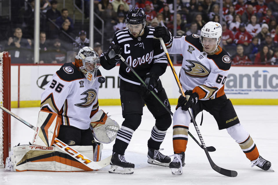 Anaheim Ducks goaltender John Gibson watches a shot go wide past New Jersey Devils center Nico Hischier (13) and Ducks defenseman Jackson LaCombe (60) during the second period of an NHL hockey game, Sunday, Dec. 17, 2023, in Newark, N.J. (AP Photo/Adam Hunger)