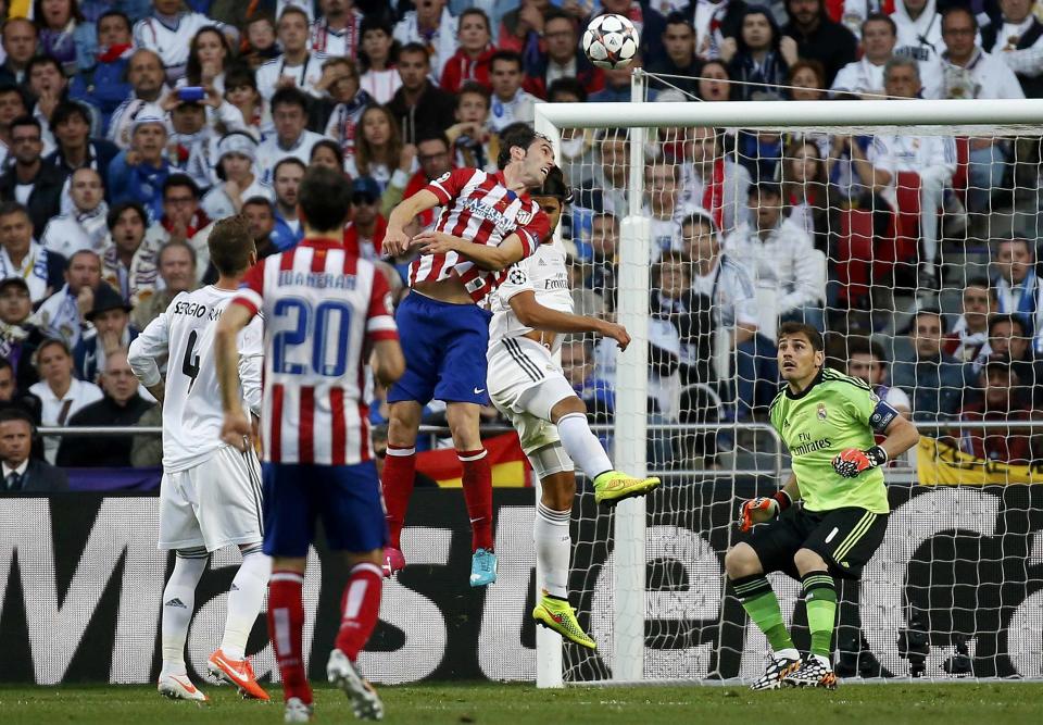 Atletico Madrid's Diego Godin (C) jumps and shoots the first goal for the team during their Champions League final soccer match against Real Madrid at the Luz Stadium in Lisbon May 24, 2014. REUTERS/Paul Hanna (PORTUGAL - Tags: SPORT SOCCER TPX IMAGES OF THE DAY)