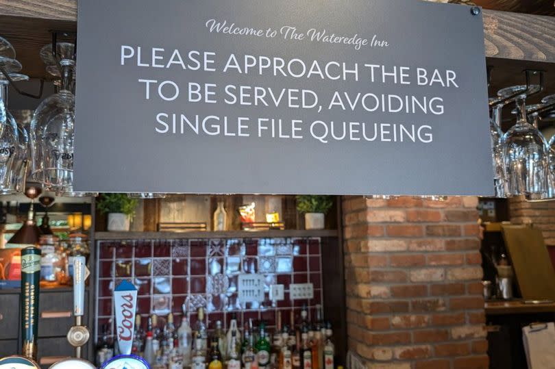 A sign advising people not to queue single file at The Wateredge Inn in Ambleside