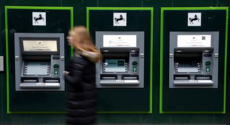 A woman walks past a row of cash machines outside a branch of Lloyds Bank in Manchester, Britain, February 21, 2017. REUTERS/Phil Noble/Files