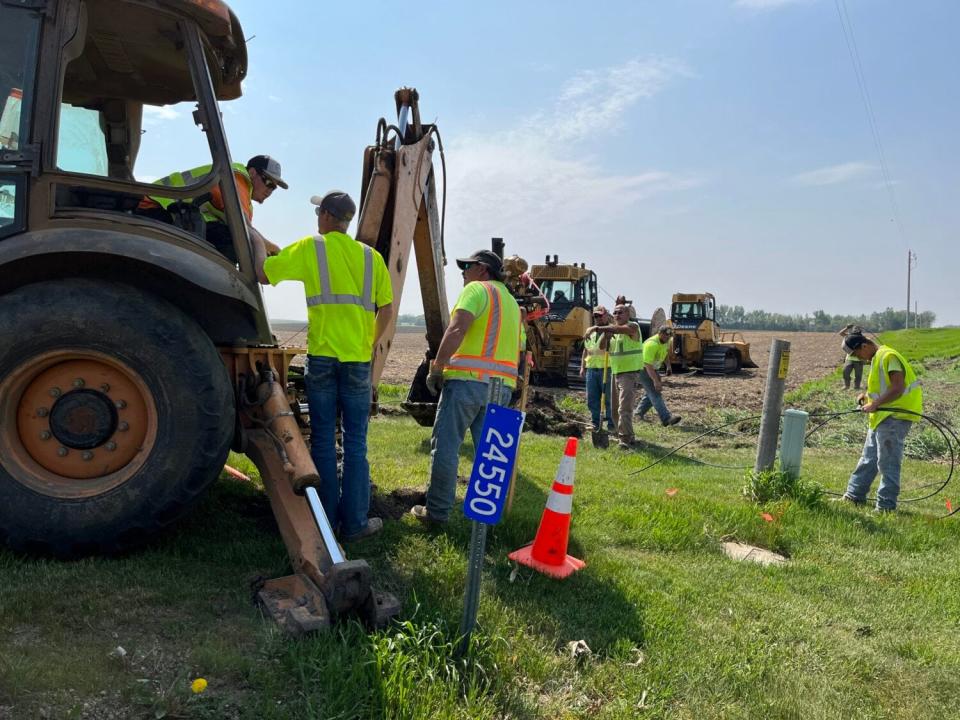 Workers lay fiber-optic cable at a broadband expansion site near Colton