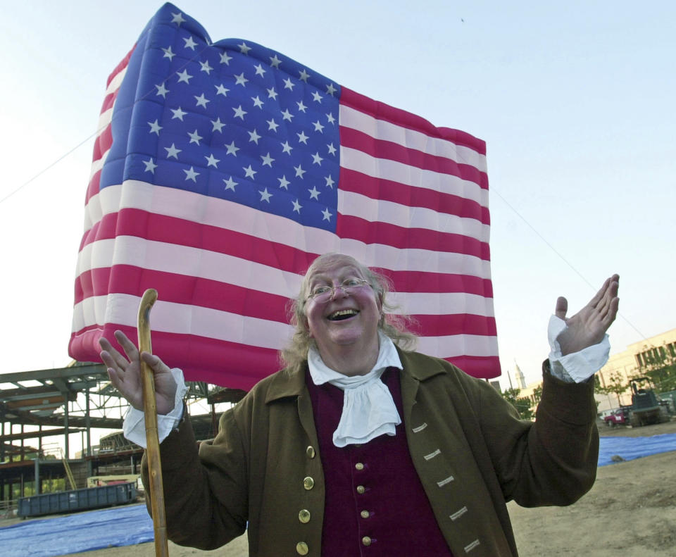 FILE – In this July 3, 2002, file photo, re-enactor Ralph Archbold, portraying Benjamin Franklin, waits to board the world's largest U.S. flag-shaped hot air balloon, during an event marking the one-year countdown to the opening of the National Constitution Center under construction on Independence Mall in Philadelphia. Archbold, who portrayed Franklin in Philadelphia for more than 40 years, died Saturday, March 25, 2017, at age 75, according to the Alleva Funeral Home in Paoli, Pa. (AP Photo/Brad C Bower, File)
